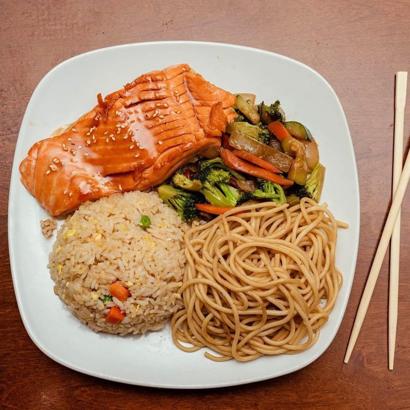 Oishii Hibachi Grill's salmon hibachi dinner with fried rice, noodles, and mixed vegetables, with chopsticks.
